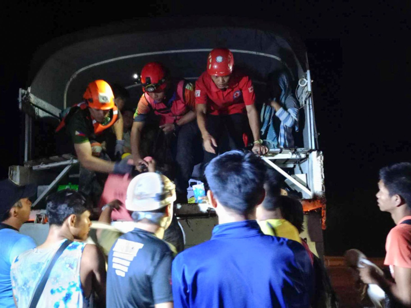 Rettungskräfte helfen Bewohnern des Dorfes Maco, sich nach dem Erdrutsch in Sicherheit zu bringen. - Foto: Uncredited/PHILIPPINE RED CROSS/AP/dpa