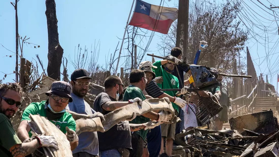 Fußballfans von CD Santiago Wanderers packen mit an und helfen bei den Aufräumarbeiten in Vina del Mar, Chile. - Bild: Esteban Felix/AP/dpa