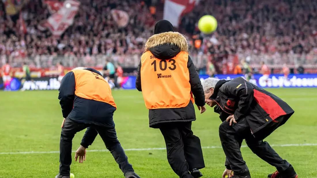 Fans vom VfL Wolfsburg werfen Tennisbälle auf das Spielfeld. - Bild: Andreas Gora/dpa