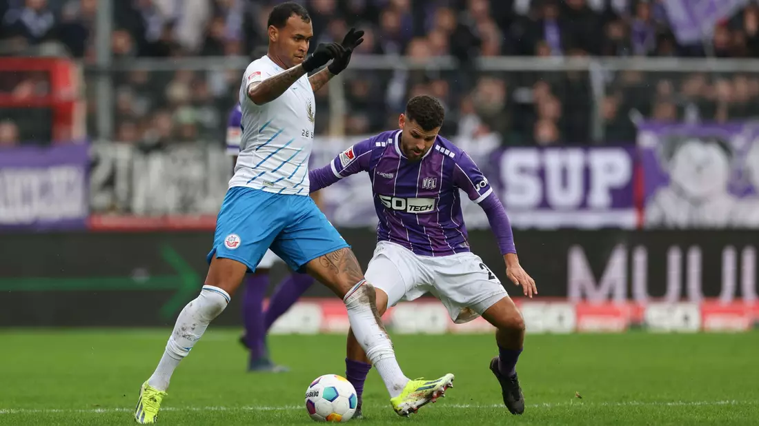 Der Rostocker Júnior Brumado (l) behauptet den Ball gegen Dave Gnaase. - Bild: Friso Gentsch/dpa
