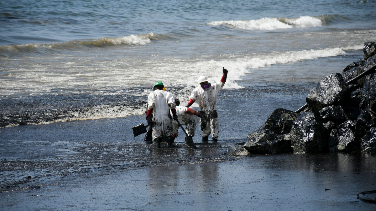 Arbeiter beseitigen einen Ölteppich, der den Strand von Rockly Bay in Scarborough im Südwesten Tobagos erreicht hat. - Foto: Akash Boodan/AP/dpa