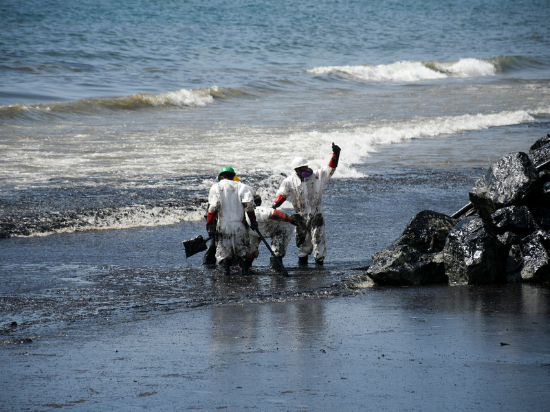 Arbeiter beseitigen einen Ölteppich, der den Strand von Rockly Bay in Scarborough im Südwesten Tobagos erreicht hat. - Foto: Akash Boodan/AP/dpa