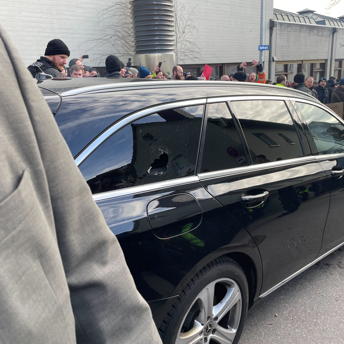 Ein Auto mit eingeschlagener Scheibe vor der Veranstaltungshalle. - Foto: David Nau/dpa