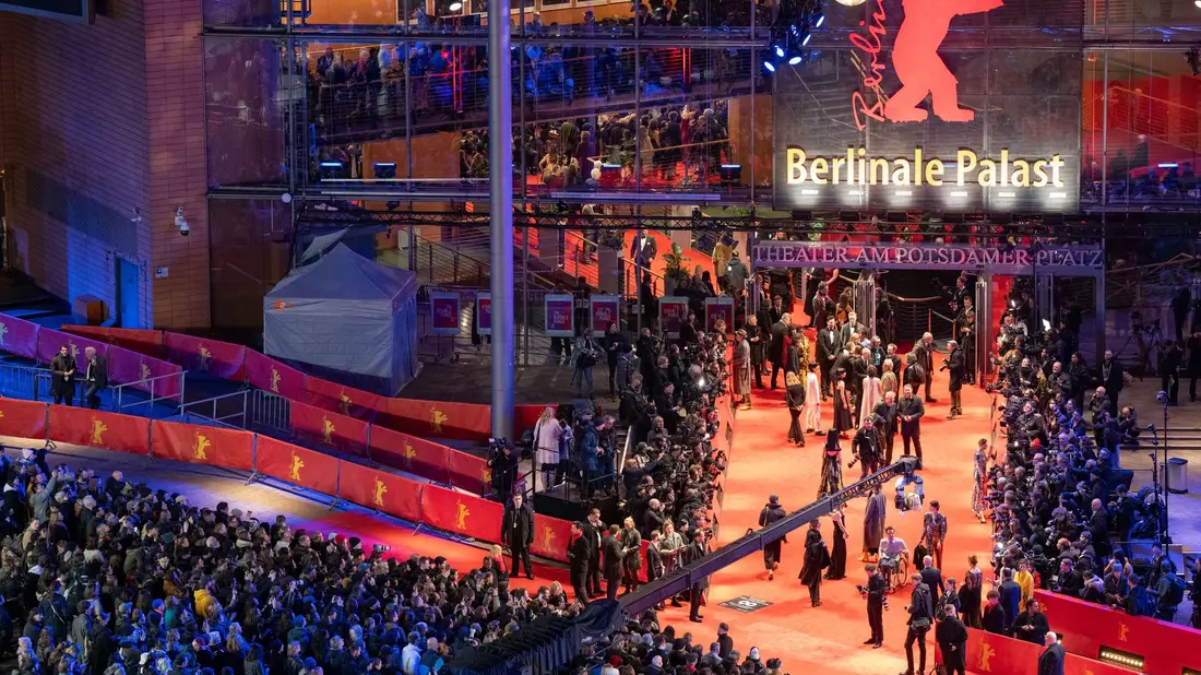 Erste Gäste stehen während der Eröffnung der 74. Berlinale auf dem roten Teppich vor dem Berlinale-Palast. - Bild: Soeren Stache/dpa