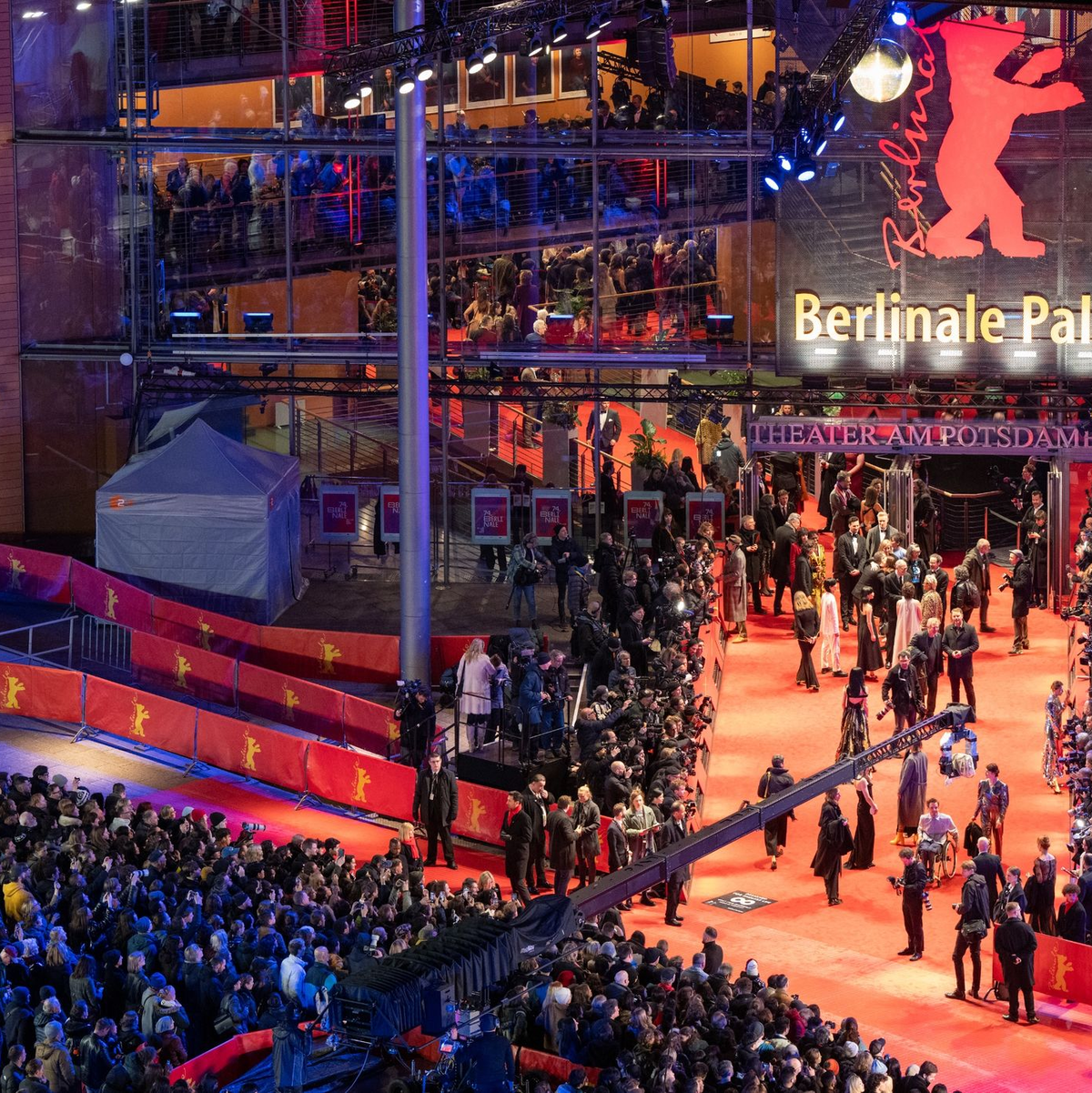 Erste Gäste stehen während der Eröffnung der 74. Berlinale auf dem roten Teppich vor dem Berlinale-Palast. - Foto: Soeren Stache/dpa