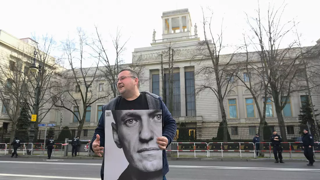 Ein Aktivist steht mit einem Plakat von Kremlkritiker Alexej Nawalny vor der russichen Botschaft in Berlin und protestiert. - Bild: Paul Zinken/dpa