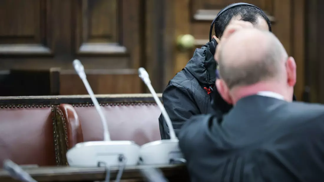 Einer der beiden Angeklagten (verdeckt) spricht mit seinem Anwalt Hannes Linke vor Prozessbeginn im Gerichtssaal des Strafjustizgebäudes. - Bild: Christian Charisius/dpa-Pool/dpa