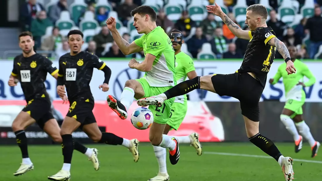 Die Dortmunder um Marco Reus (r) mussten sich in Wolfsburg mit einem 1:1 zufrieden geben. - Bild: Swen Pförtner/dpa