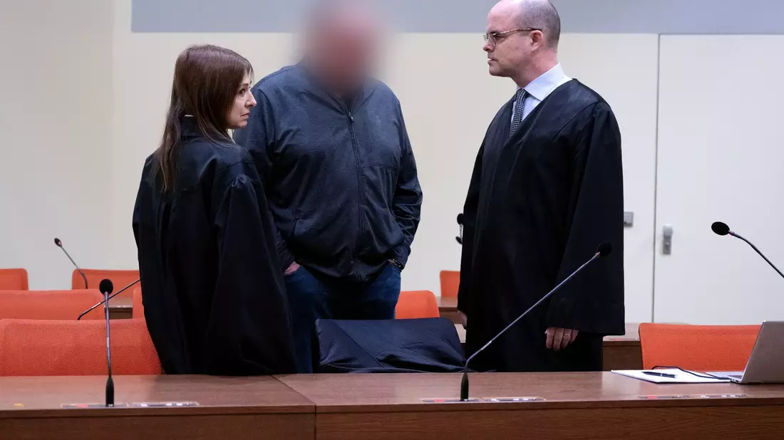 Der angeklagte Lokführer (M) steht mit seiner Anwältin und seinem Anwalt im Gerichtssaal in München. - Bild: Sven Hoppe/dpa