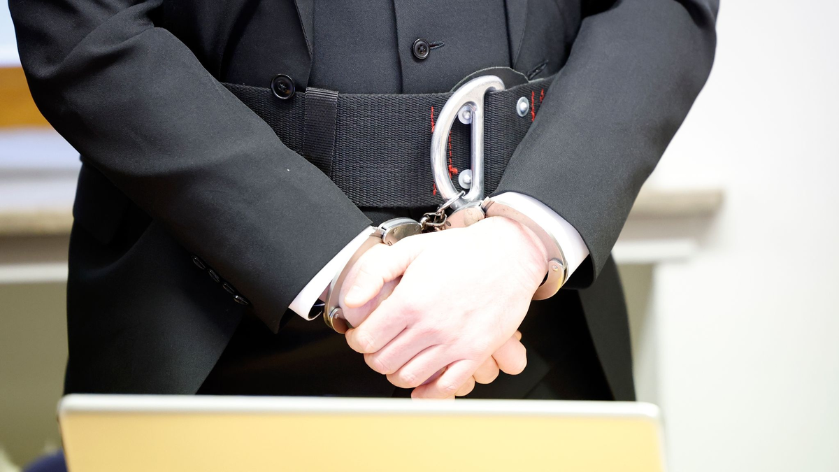 Der Angeklagte steht an Händen und Füßen gefesselt im Gerichtssaal im Landgericht Schweinfurt. - Foto: Heiko Becker/dpa