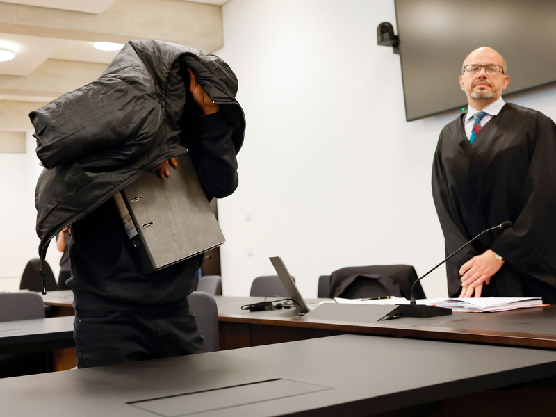 Der ehemalige Security-Mann bedeckt im Gerichtsaal seinen Kopf mit einer Jacke. - Foto: Daniel Löb/dpa