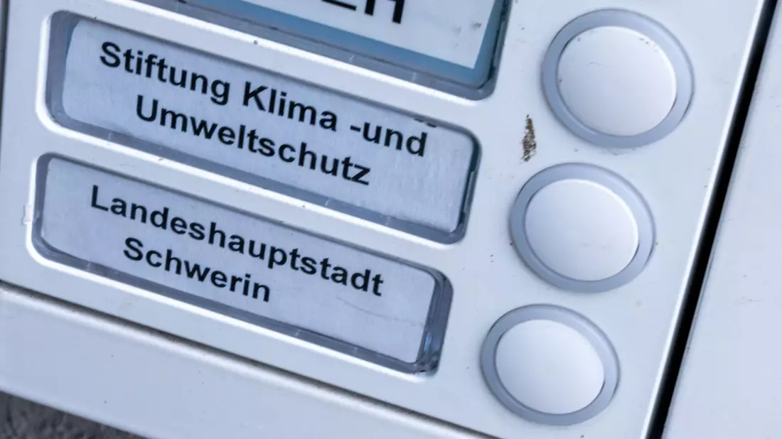 Das Klingelschild der Stiftung Klima- und Umweltschutz am Eingang eines Wohn- und Geschäftshauses. Die geplante Auflösung der Klimastiftung MV ist heftig umstritten. - Bild: Jens Büttner/dpa