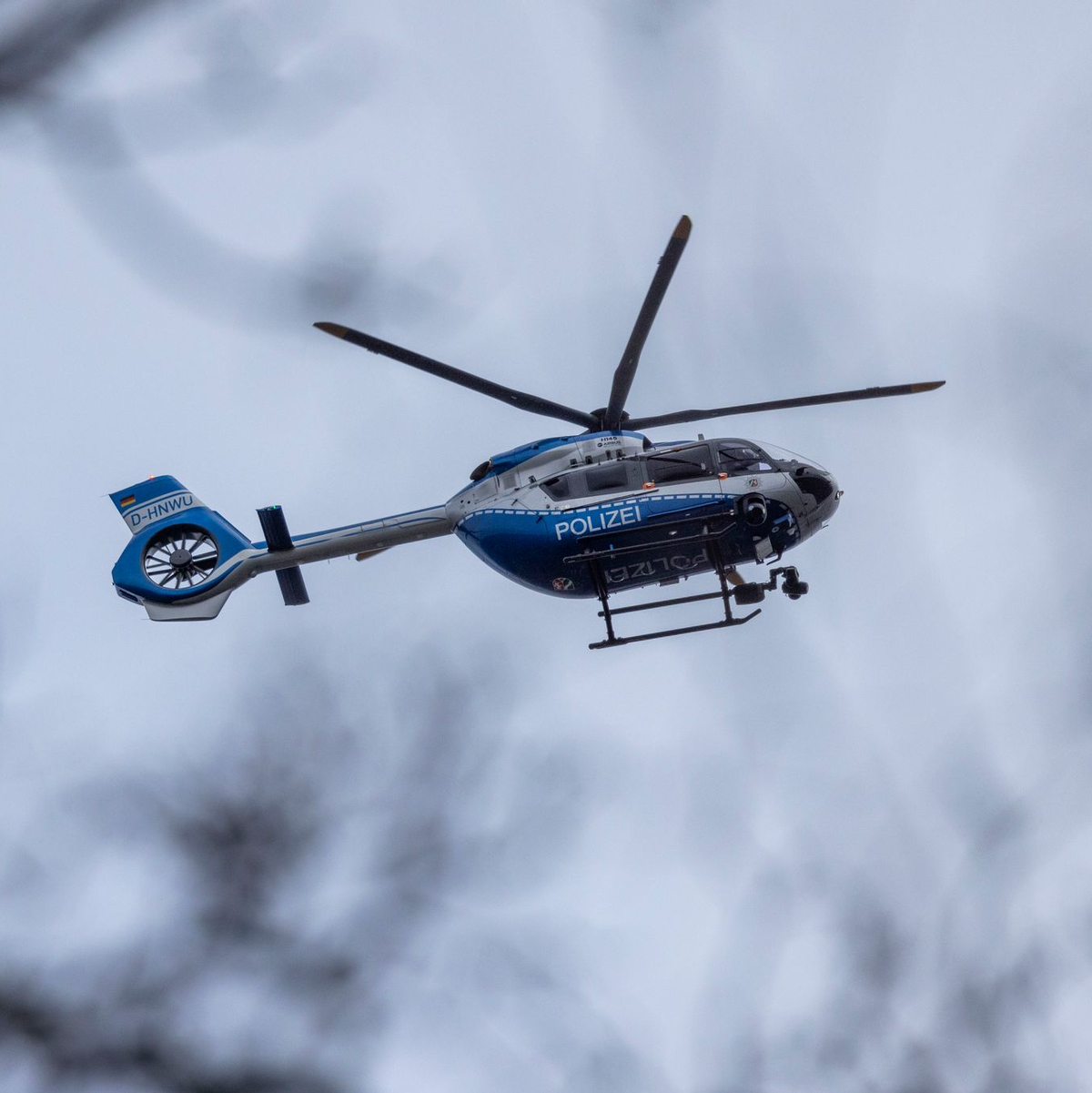 Der Polizei-Hubschrauber kreist über der Schule in Wuppertal. - Foto: Christoph Reichwein/dpa