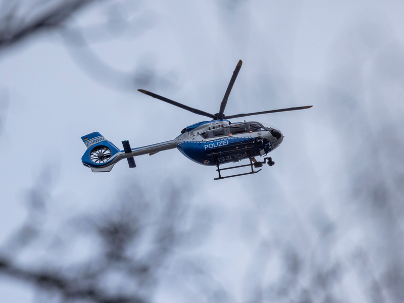 Der Polizei-Hubschrauber kreist über der Schule in Wuppertal. - Foto: Christoph Reichwein/dpa