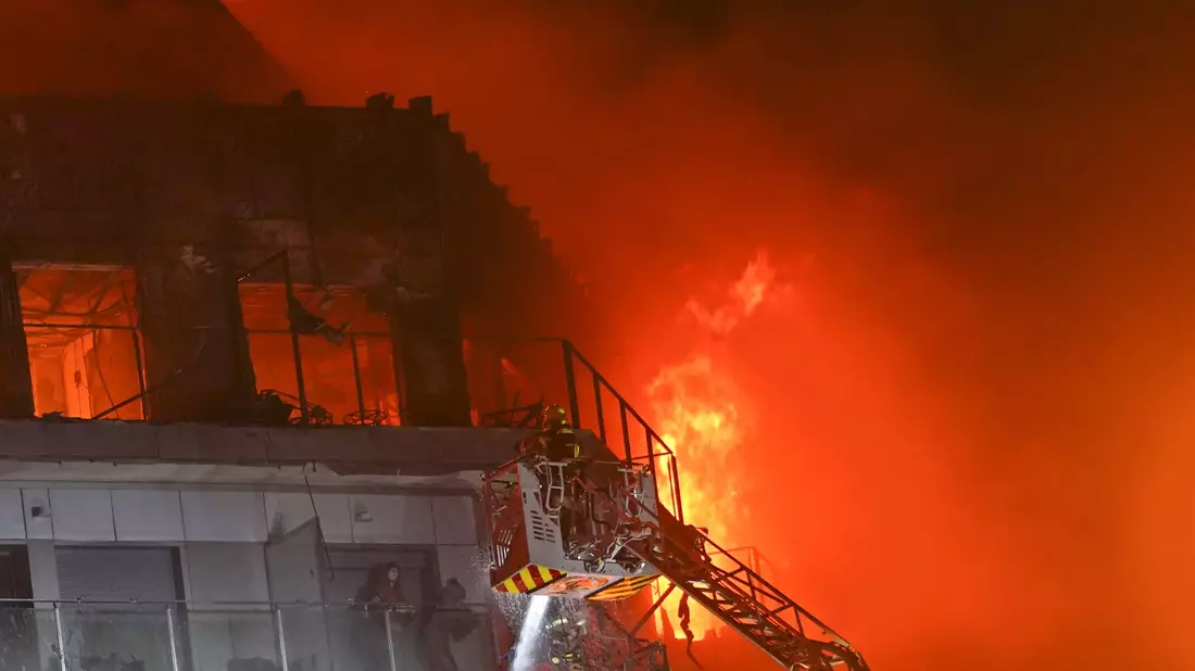 Feuerwehrleute retten zwei Menschen aus dem brennenden Hochhaus. - Bild: Alberto Saiz/AP/dpa