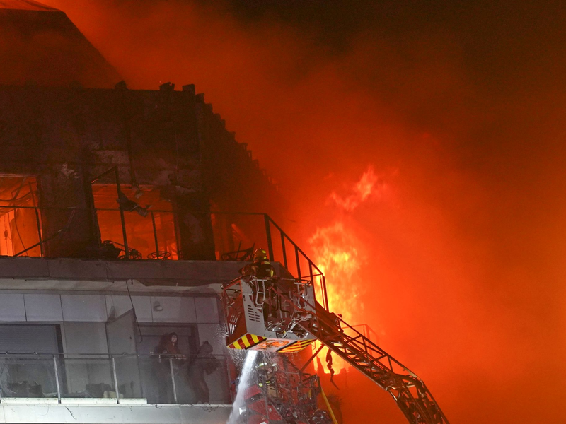 Feuerwehrleute retten zwei Menschen aus dem brennenden Hochhaus. - Foto: Alberto Saiz/AP/dpa