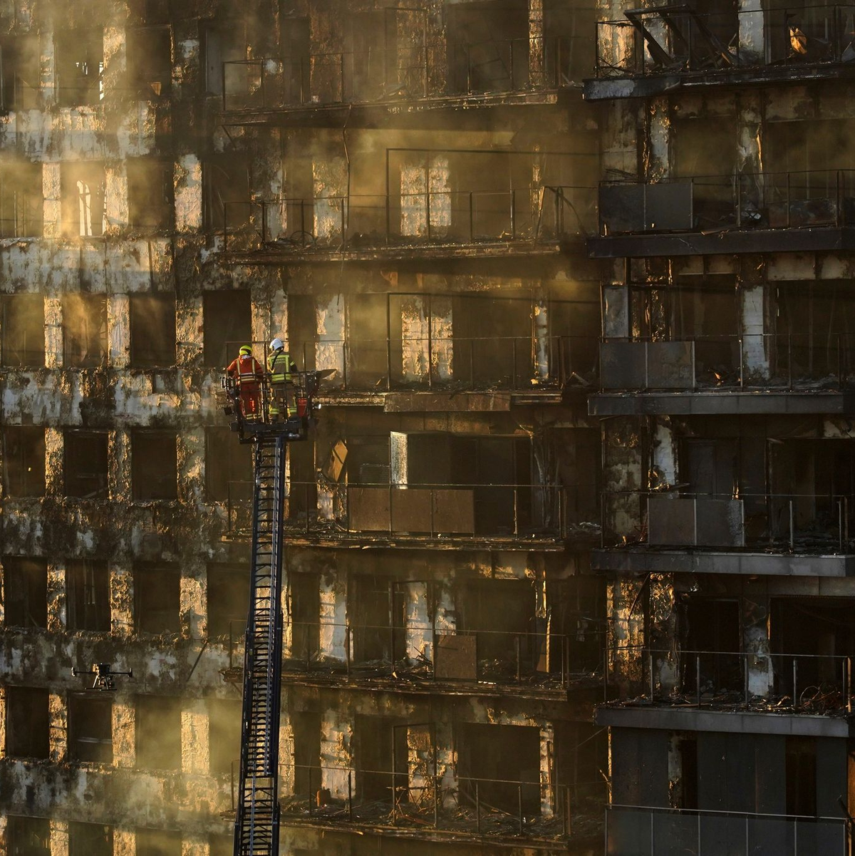 Feuerwehrleute stehen während Löscharbeiten auf einer Hubleiter. - Foto: Alberto Saiz/AP/dpa
