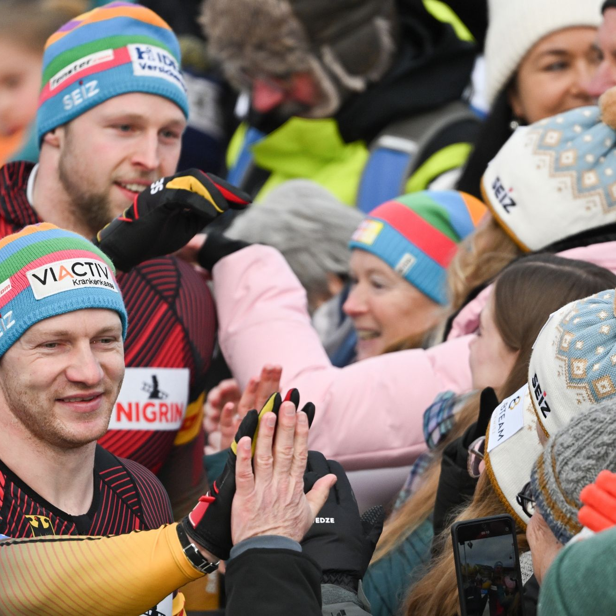Francesco Friedrich (vorne l) und Alexander Schüller (hinten l) klatschen nach ihrem Sieg mit Fans ab. - Foto: Robert Michael/dpa