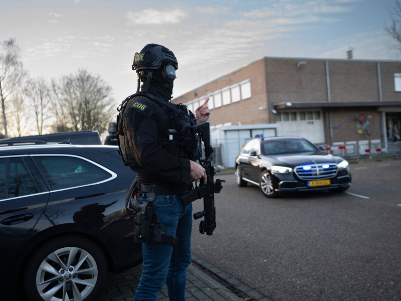 Maskierte und bewaffnete niederländische Polizisten bewachen einen Transport mit einigen der Verdächtigen, die vor dem Hochsicherheitsgebäude des Gerichts in Amsterdam eintreffen. - Foto: Peter Dejong/AP/dpa