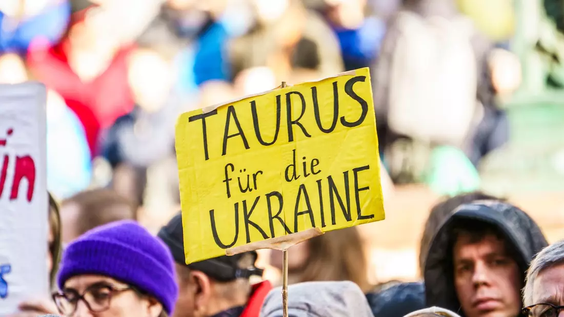 Bei einer Demonstration zum zweiten Jahrestag des russischen Angriffskrieges auf die Ukraine fordern Teilnehmer die Lieferung von Taurus-Marschflugkörper. - Bild: Andreas Arnold/dpa