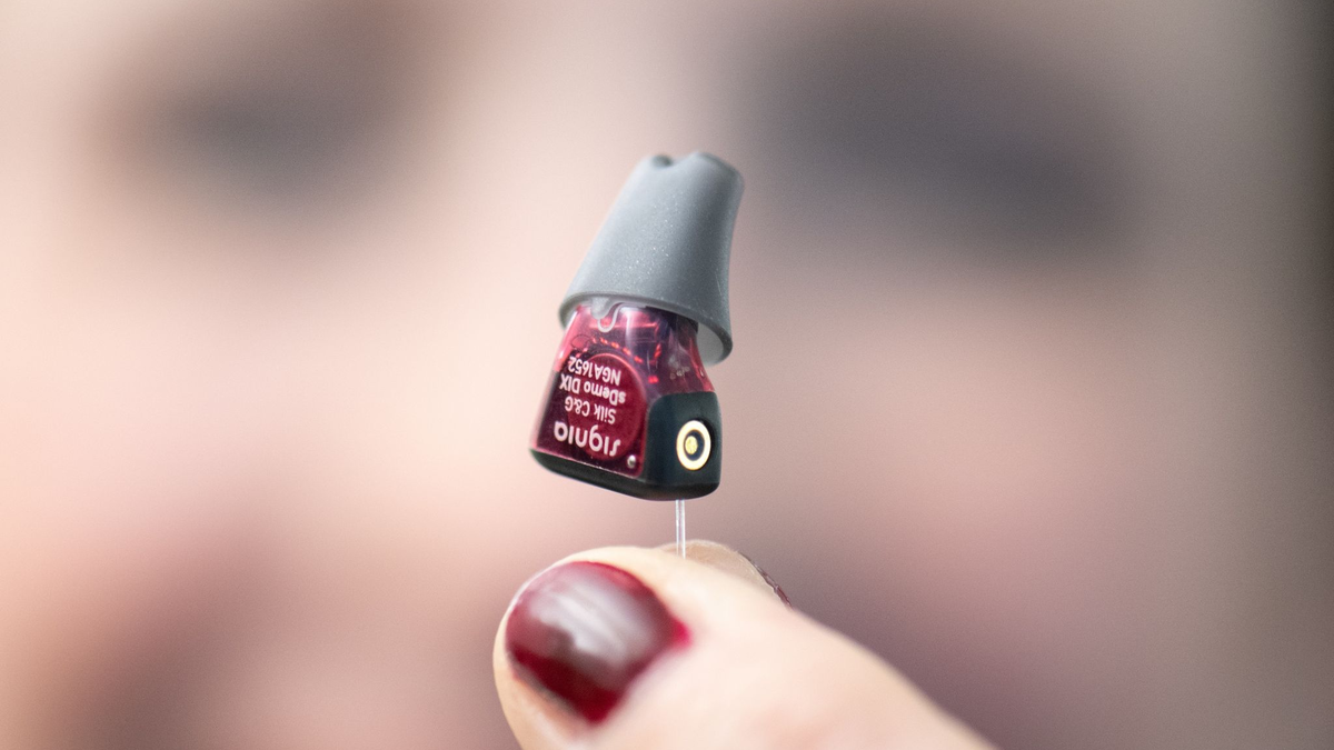 Die Hörakustikmeisterin Eva Keil-Becker mit einem winzigen Hörgerät. - Foto: Boris Roessler/dpa