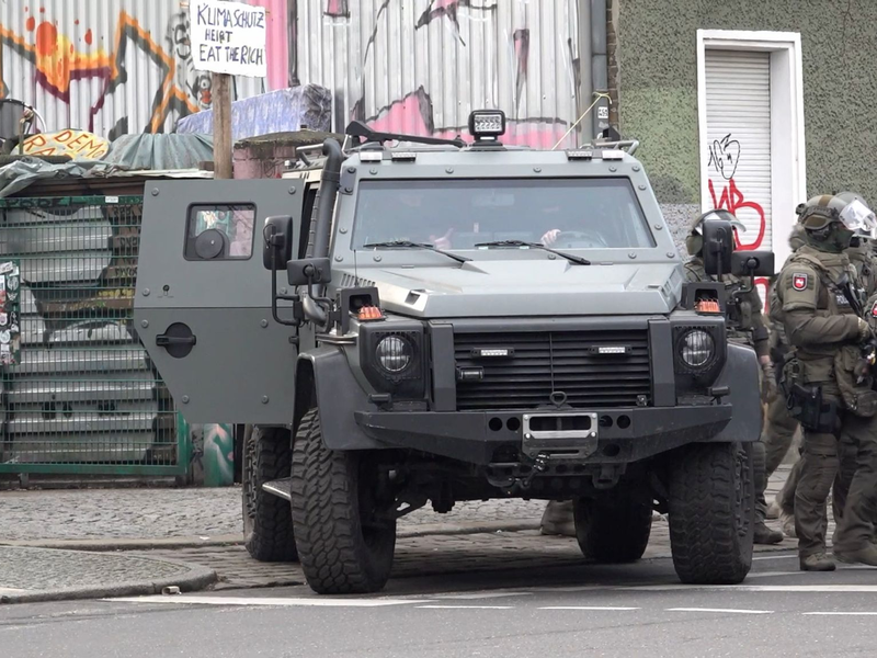 Polizisten an einem gepanzerten Fahrzeug. - Foto: Paul Zinken/dpa