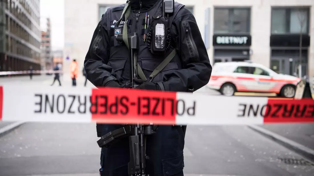 Ein schwer bewaffneter Polizist hinter einem Absperrband in der Züricher Innenstadt (Symbolbild). - Bild: Ennio Leanza/KEYSTONE/dpa