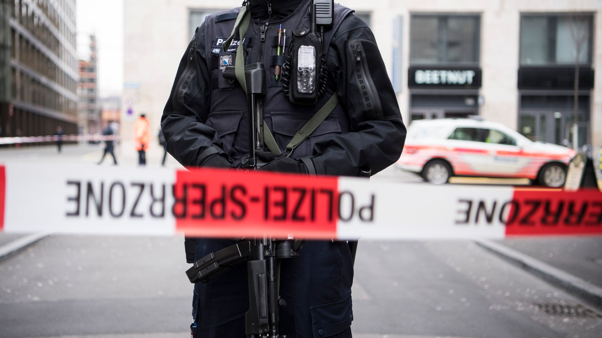 Ein schwer bewaffneter Polizist hinter einem Absperrband in der Züricher Innenstadt (Symbolbild). - Foto: Ennio Leanza/KEYSTONE/dpa
