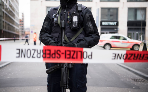 Ein schwer bewaffneter Polizist hinter einem Absperrband in der Züricher Innenstadt (Symbolbild). - Foto: Ennio Leanza/KEYSTONE/dpa