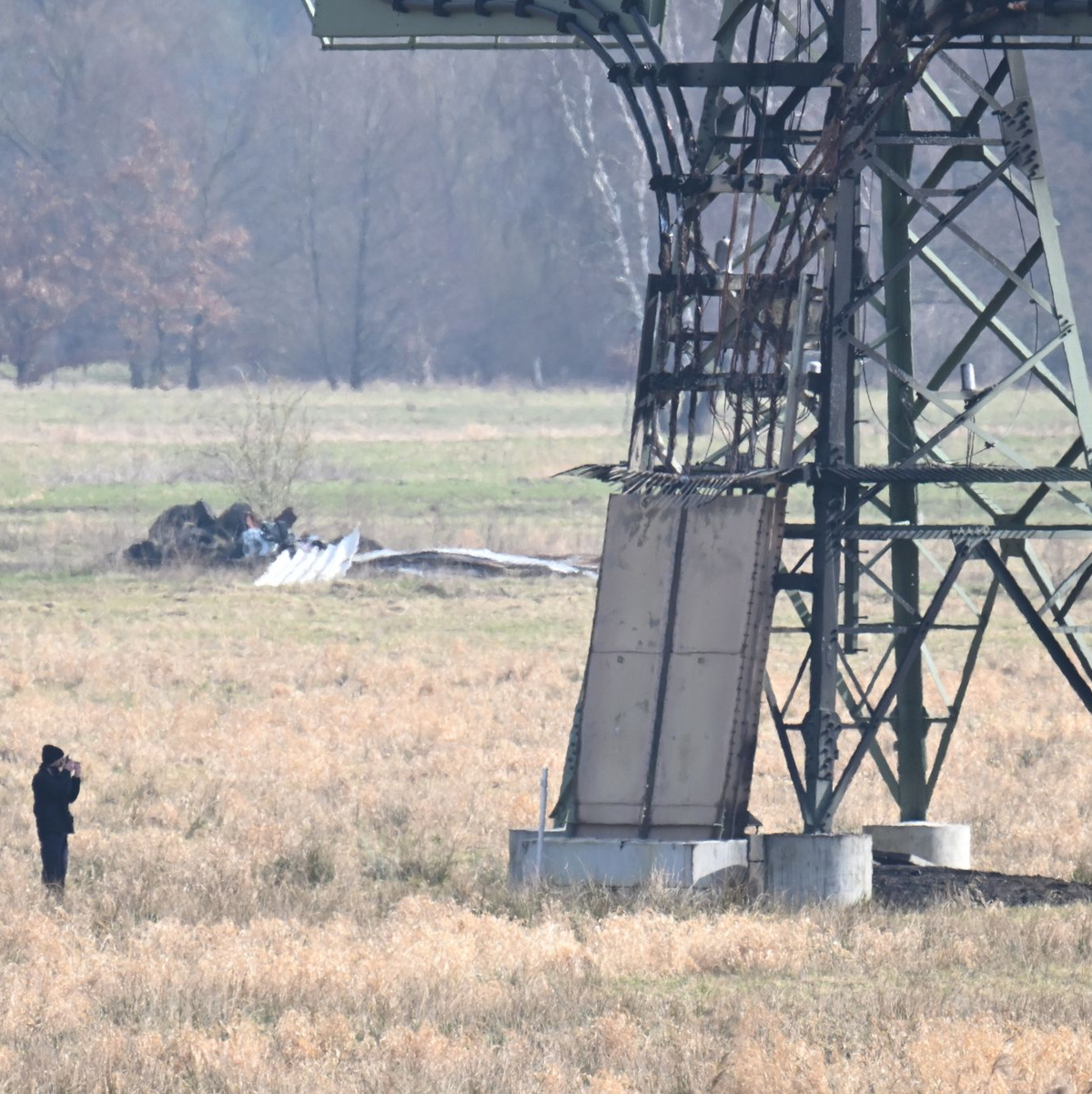 Polizisten ermitteln an dem beschädigten Strommast auf einem Feld in Spreenhagen. - Foto: Sebastian Gollnow/dpa