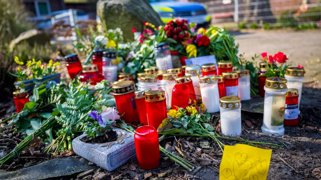Blumen und Kerzen liegen vor einem Einfamilienhaus in Scheeßel. - Bild: Sina Schuldt/dpa
