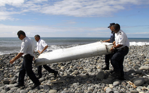 Techniker tragen ein Wrackteil, die Flügelklappe eines Flugzeugs, über einen Strand bei Saint-André,  Réunion. - Foto: Raymond Wae Tion/MAXPPP/QUOTIDIEN DE LA REUNION/dpa