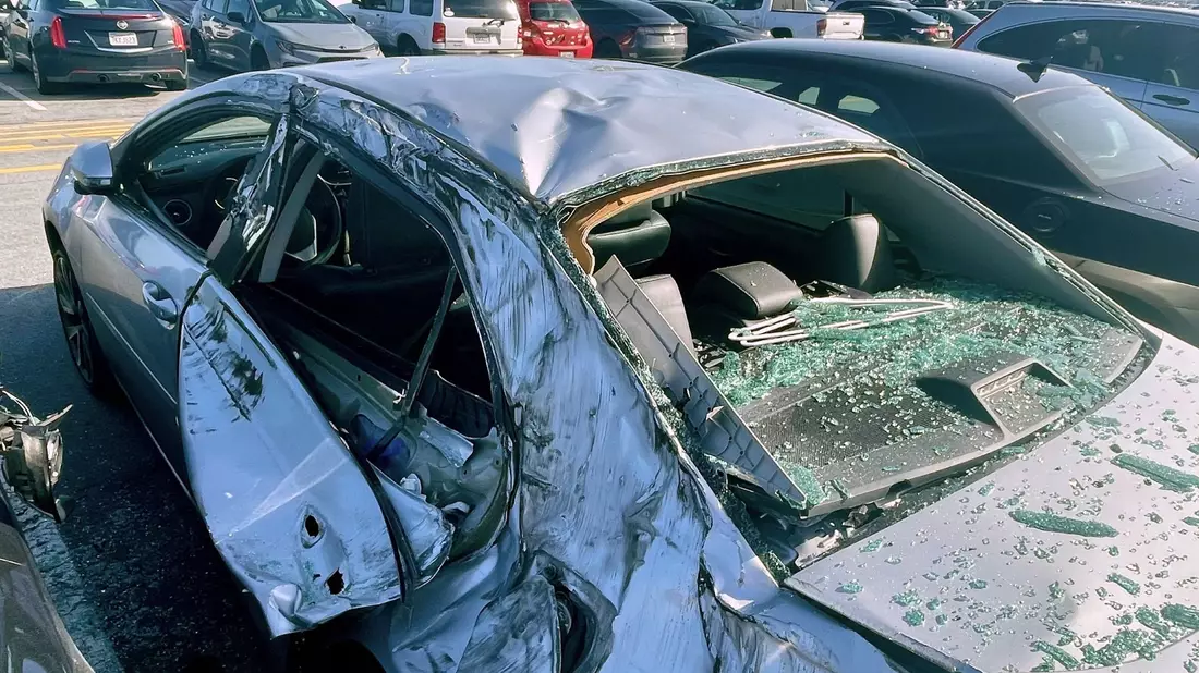 Am Boden beschädigte das abgerissene Rad mehrere Autos auf einem Parkplatz neben dem Flughafen. - Bild: Haven Daley/AP