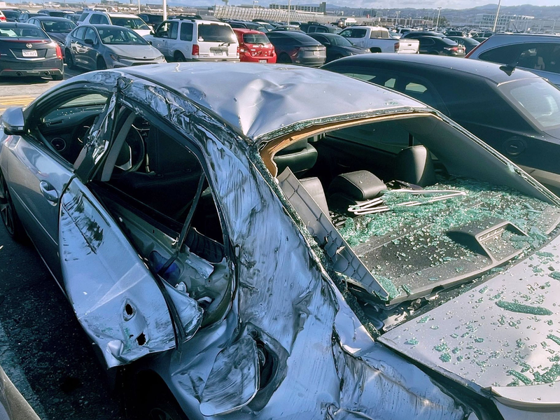 Am Boden beschädigte das abgerissene Rad mehrere Autos auf einem Parkplatz neben dem Flughafen. - Foto: Haven Daley/AP
