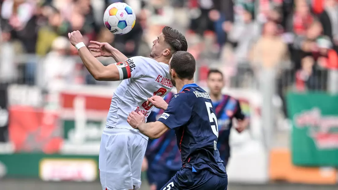 Der Augsburger Ermedin Demirovic (l) behauptet den Ball gegen Heidenheims Benedikt Gimber. - Bild: Harry Langer/dpa
