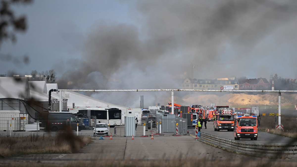 Feuerwehrmänner löschen die letzten Brandstellen in der Flüchtlingsunterkunft am ehemaligen Flughafen Tegel. - Foto: Sebastian Gollnow/dpa