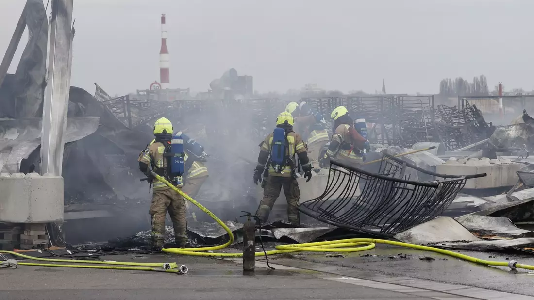 Die Feuerwehr löscht die Brandstelle bei der Flüchtlingsunterkunft am ehemaligen Flughafen Tegel. Die Nachlöscharbeiten sind inzwischen abgeschlossen. - Bild: Carsten Koall/dpa