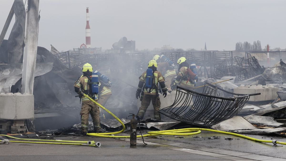 Die Feuerwehr löscht die Brandstelle bei der Flüchtlingsunterkunft am ehemaligen Flughafen Tegel. Die Nachlöscharbeiten sind inzwischen abgeschlossen. - Foto: Carsten Koall/dpa