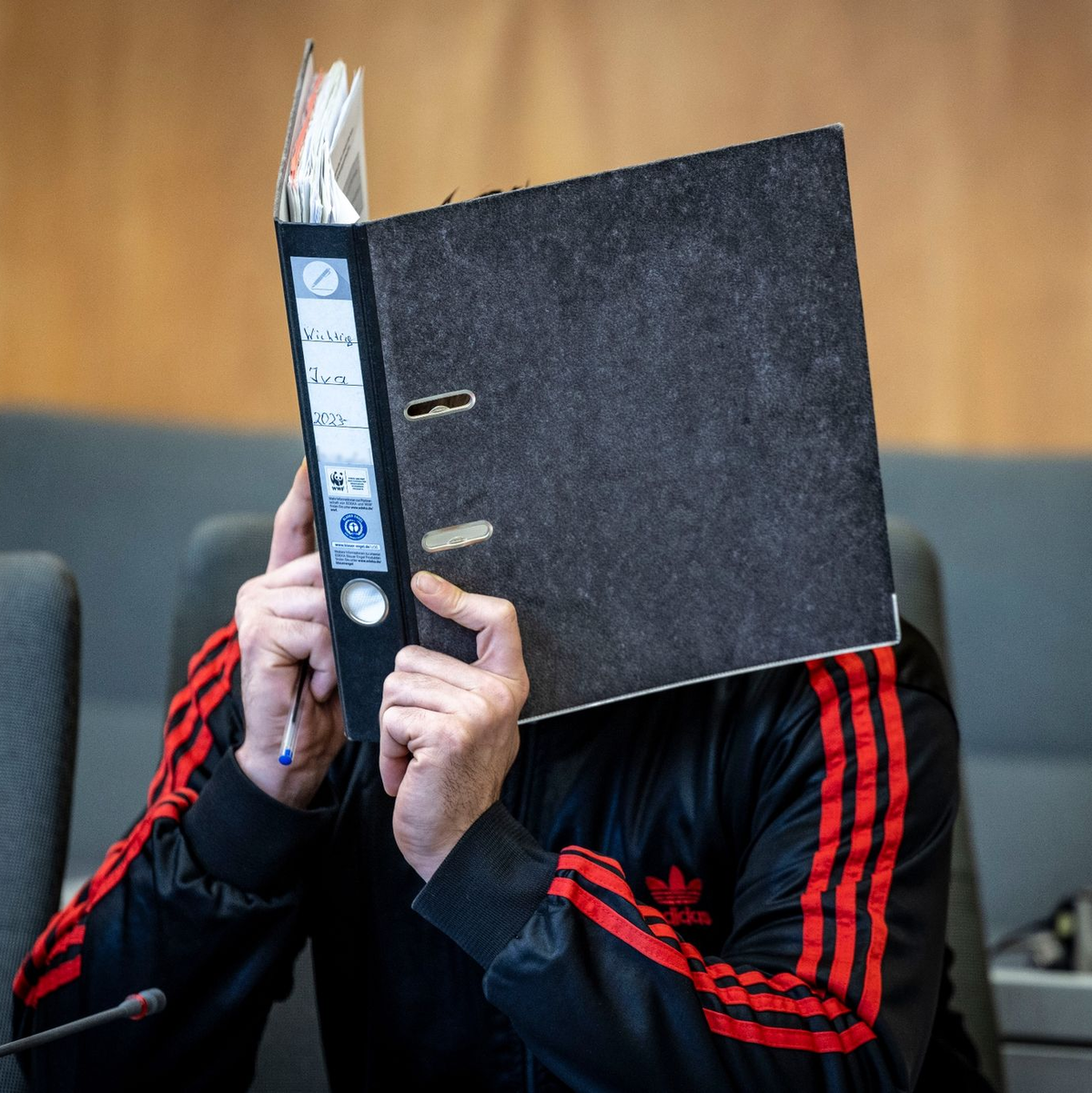 Der Angeklagte verbirgt im Landgericht sein Gesicht hinter einem Aktenordner. - Foto: Christoph Reichwein/dpa