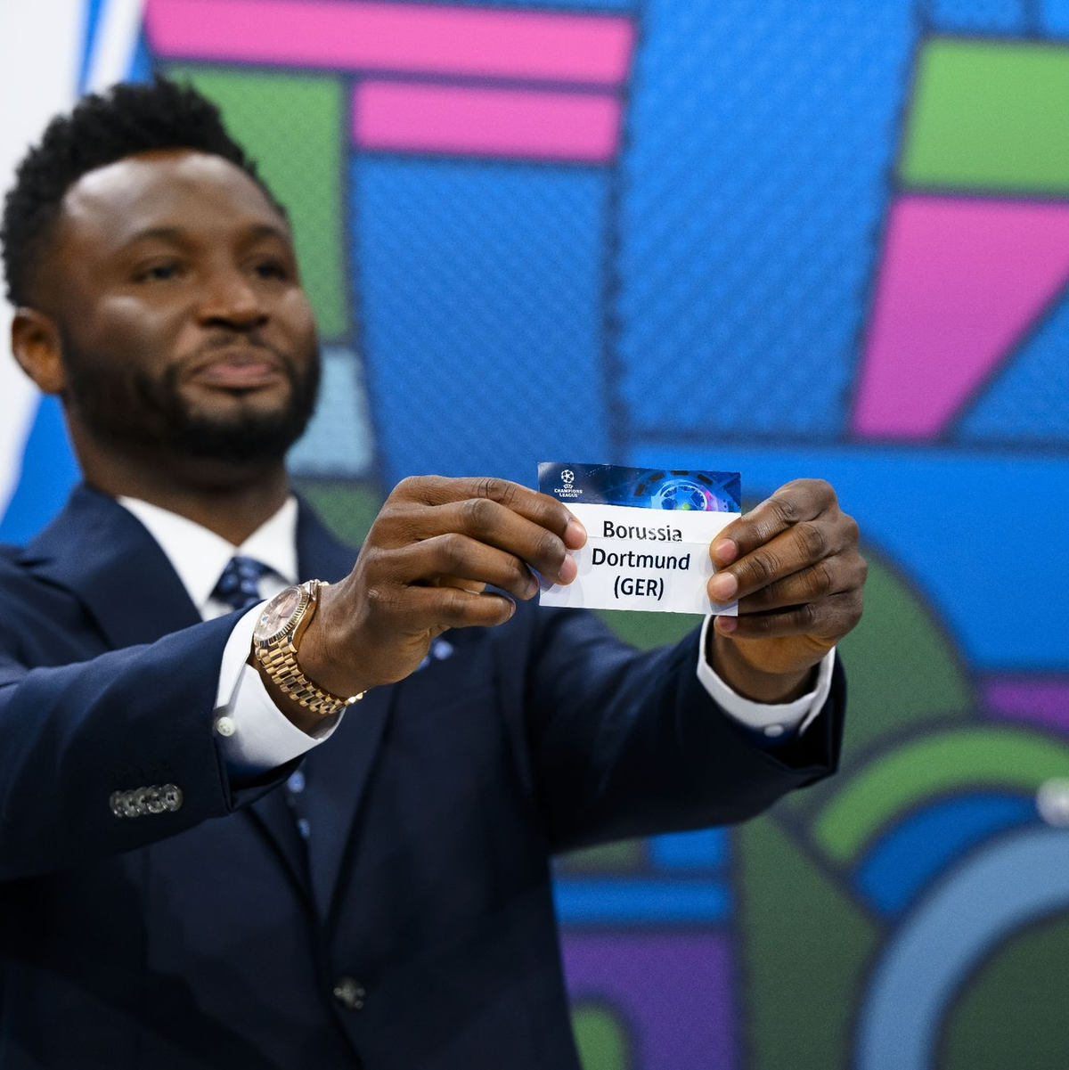 Der ehemalige nigerianische Fußballspieler und Botschafter des Champions-League-Finales in London, John Obi Mikel, zeigt das Los. - Foto: Jean-Christophe Bott/KEYSTONE/dpa