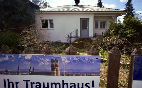 Ein zum Abriss bestimmtes Münchner Einfamilienhaus mitsamt dem Werbeplakat einer Immobiliengesellschaft. - Foto: Carsten Hoefer/dpa