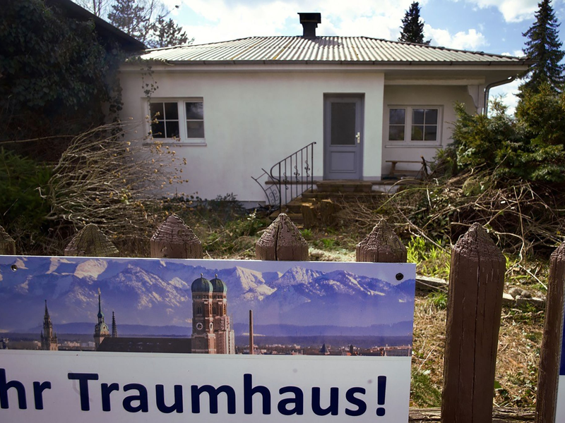 Ein zum Abriss bestimmtes Münchner Einfamilienhaus mitsamt dem Werbeplakat einer Immobiliengesellschaft. - Foto: Carsten Hoefer/dpa