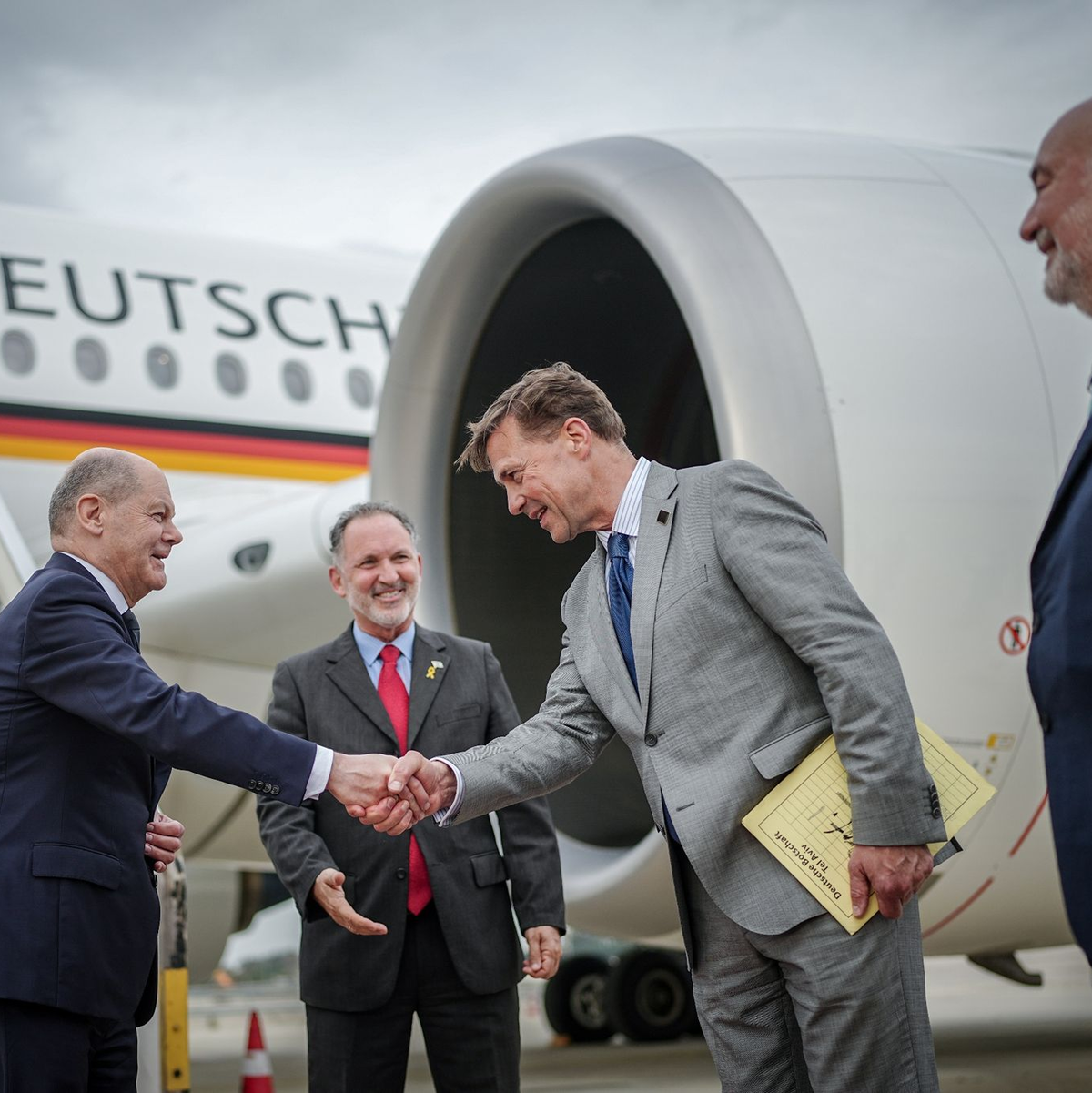 Kanzler Scholz wird auf dem Flughafen von Tel Aviv vom deutschen BOtschafter Steffen Seibert begrüßt. Rechts der israelische Botschafter in Deutschland, Ron Prosor. - Foto: Kay Nietfeld/dpa