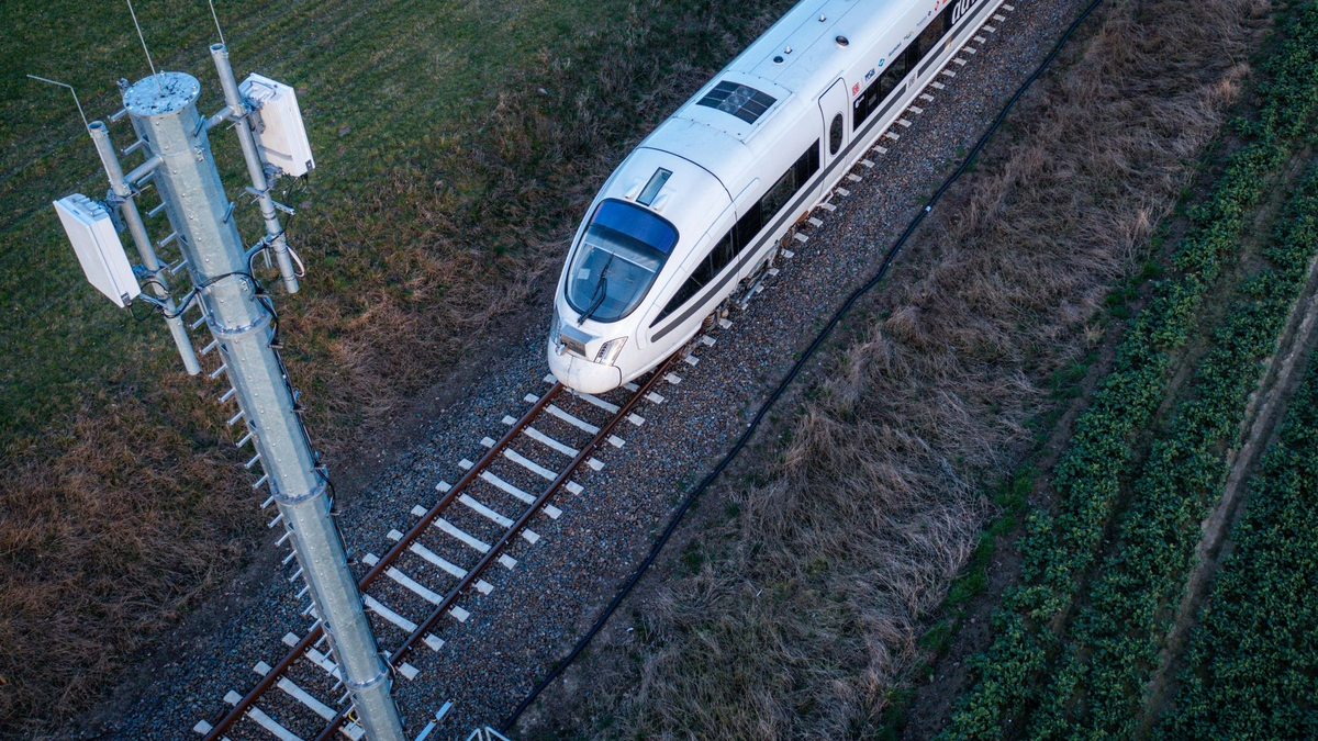 Ein Testzug der Deutschen Bahn fährt an einer der Antennenmasten für das 5G-Bahnprojekt vorbei. - Foto: Jens Büttner/dpa