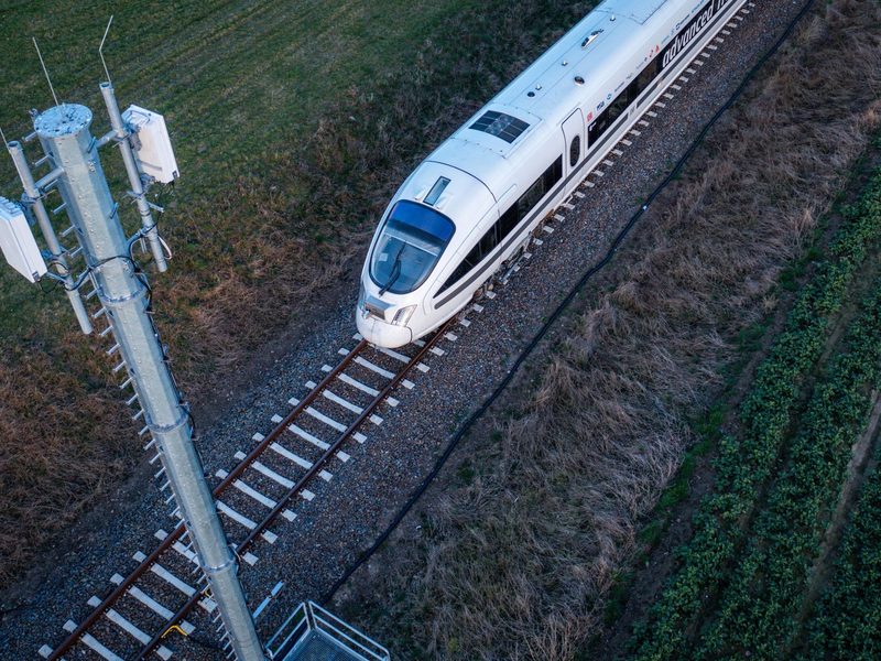 Ein Testzug der Deutschen Bahn fährt an einer der Antennenmasten für das 5G-Bahnprojekt vorbei. - Foto: Jens Büttner/dpa