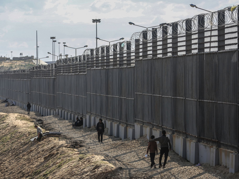 Palästinenser stehen nahe der Grenze zwischen dem Gazastreifen und Ägypten. - Foto: Mohammed Talatene/dpa