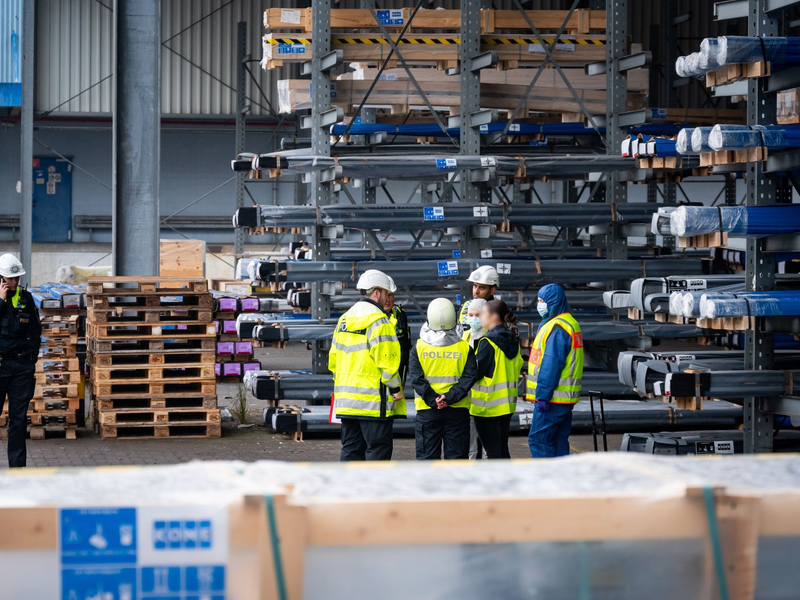 Ermittler und Polizisten stehen nahe der Unglücksstelle am Hamburger Hafen. - Foto: Jonas Walzberg/dpa