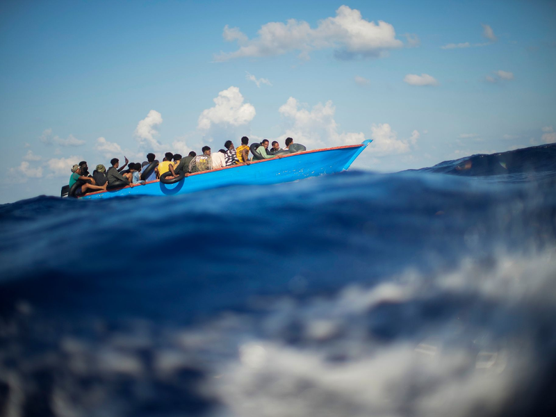 Migranten sitzen in einem Holzboot im Mittelmeer nahe der Insel Lampedusa: Die kleine Insel gehört seit Jahren zu den Brennpunkten illegaler Migration (Archivfoto). - Foto: Francisco Seco/AP/dpa