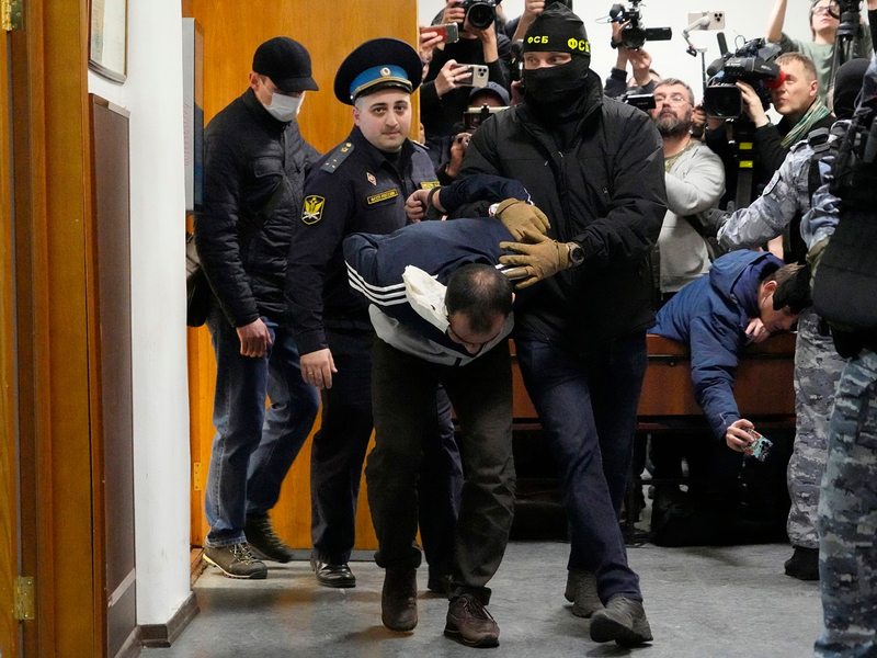 Ein Tatverdächtiger wird von Polizisten und FSB-Beamten im Basmanny-Bezirksgericht eskortiert. - Foto: Alexander Zemlianichenko/AP