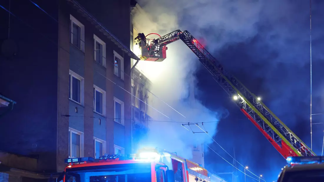 Von einer Drehleiter aus bekämpft ein Feuerwehrmann den Brand in einem Mehrfamilienhaus. - Bild: Gianni Gattus/Blaulicht Solingen/dpa